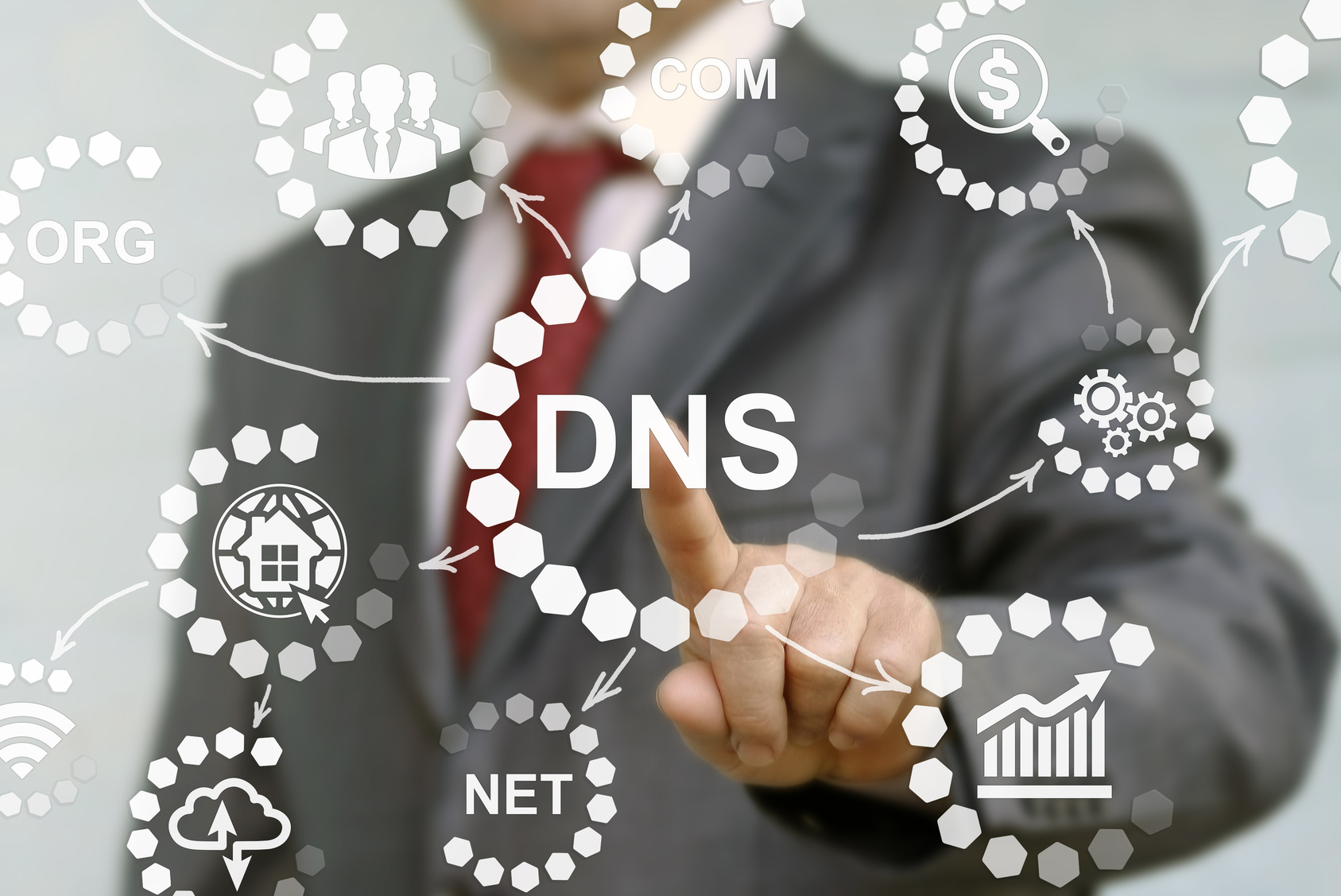 Blurry body shot of man in a suit reaching forward with index finger to click on the words, DNS, which is surrounded by various illustrations to depict what DNS involves.